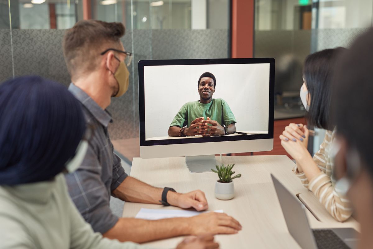 Twee mensen in gesprek aan een tafel op kantoor tijdens een intakegesprek met laptop en notities