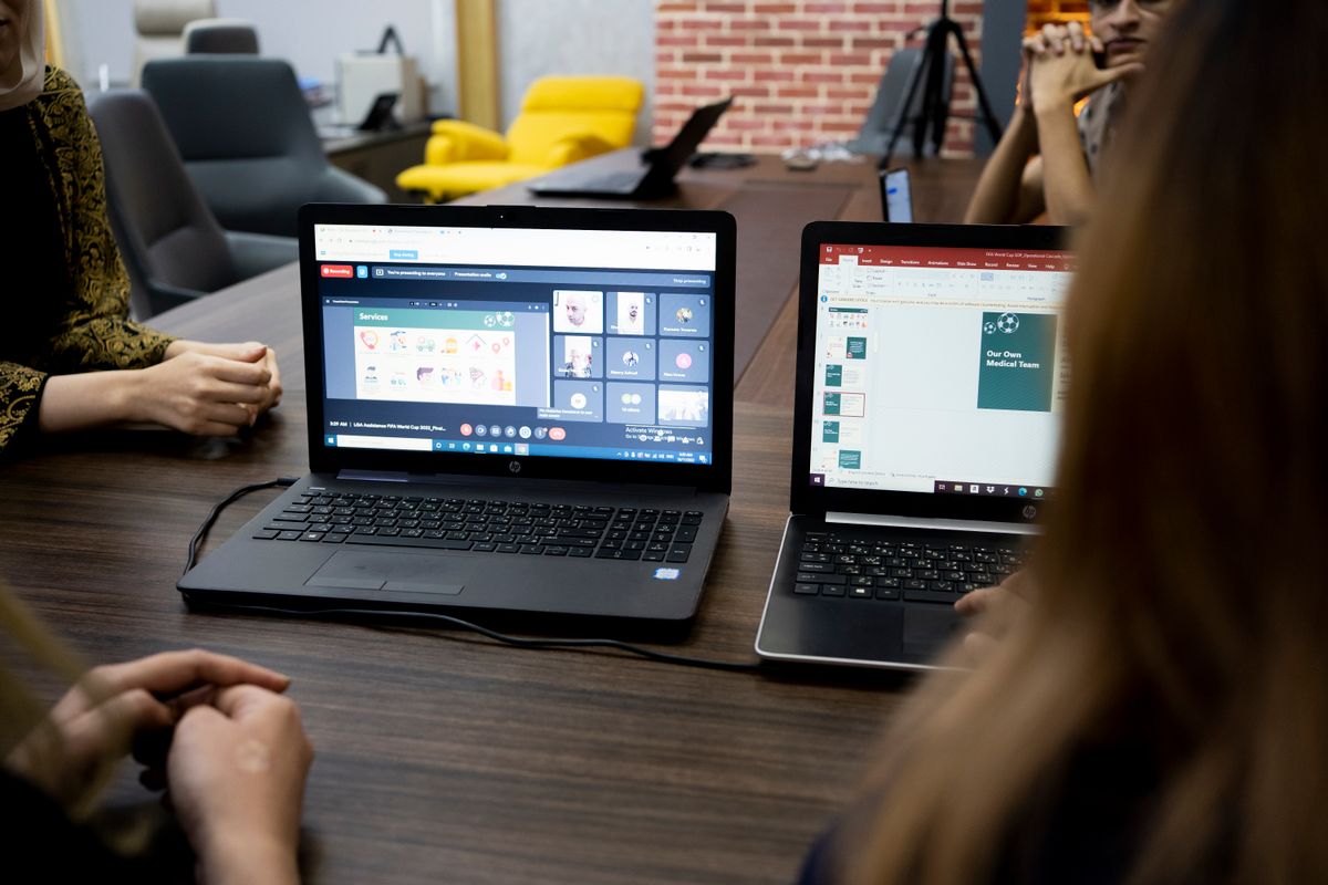 Internationaal team in een online vergadering aan een tafel met laptops