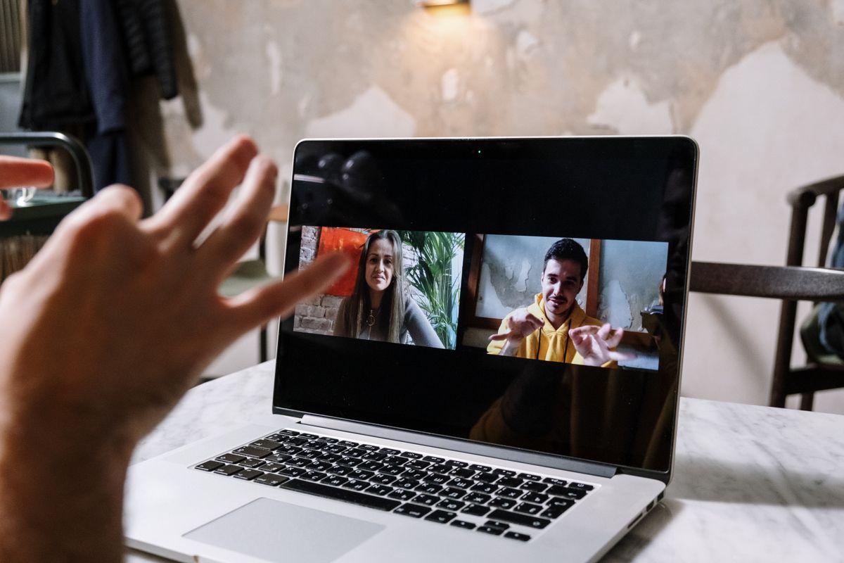 Sales medewerker voert een verkoopgesprek via een videocall op laptop en maakt notities