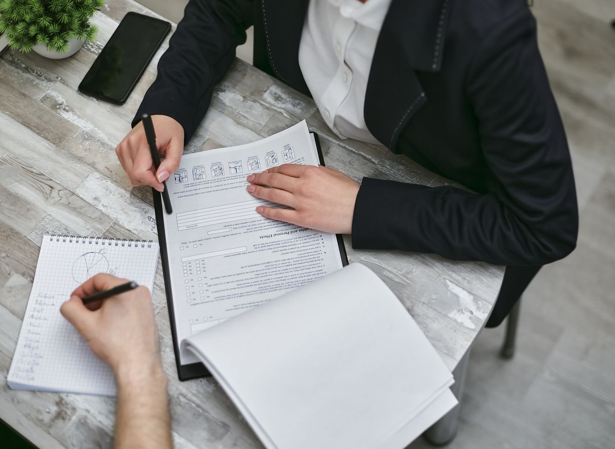 Twee collega's aan een bureau bespreken documenten en stellen samen een vergaderagenda op