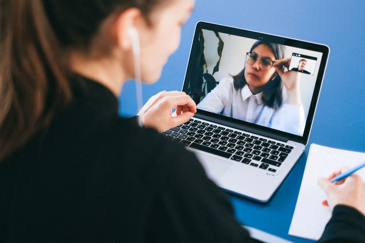 Vrouw leest notities bij een laptop om een gemiste online vergadering in te halen