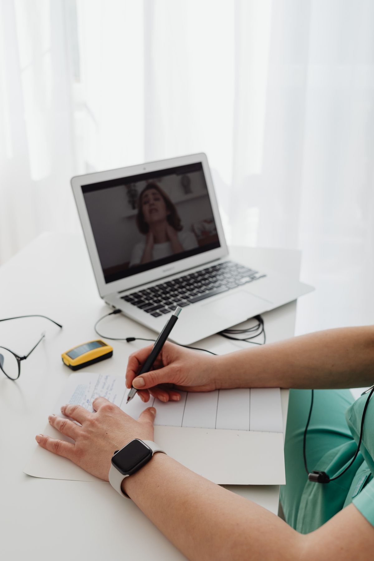 Vrouw maakt aantekeningen tijdens een videovergadering op haar laptop